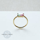 Gold ring with a rectangular gemstone on a light gray background