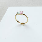 Gold ring with a pink and green gemstone on a white surface