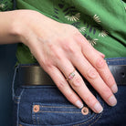 Hand with a ring on a person wearing a green shirt and blue jeans.