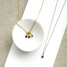 Two necklaces with gemstone pendants on a textured surface