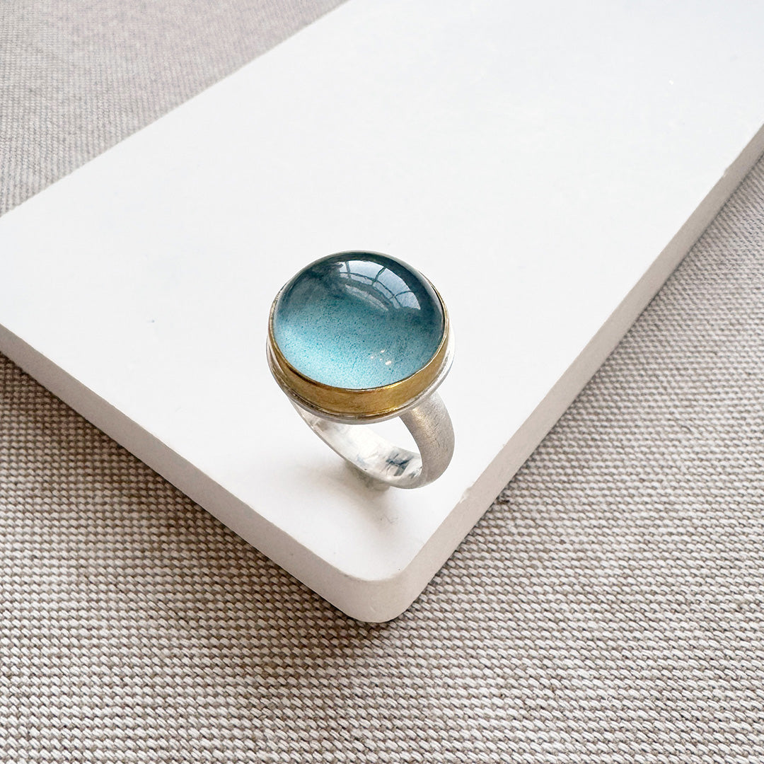 Ring with a blue aquamarine stone on a white surface