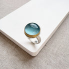 Ring with a blue aquamarine stone on a white surface