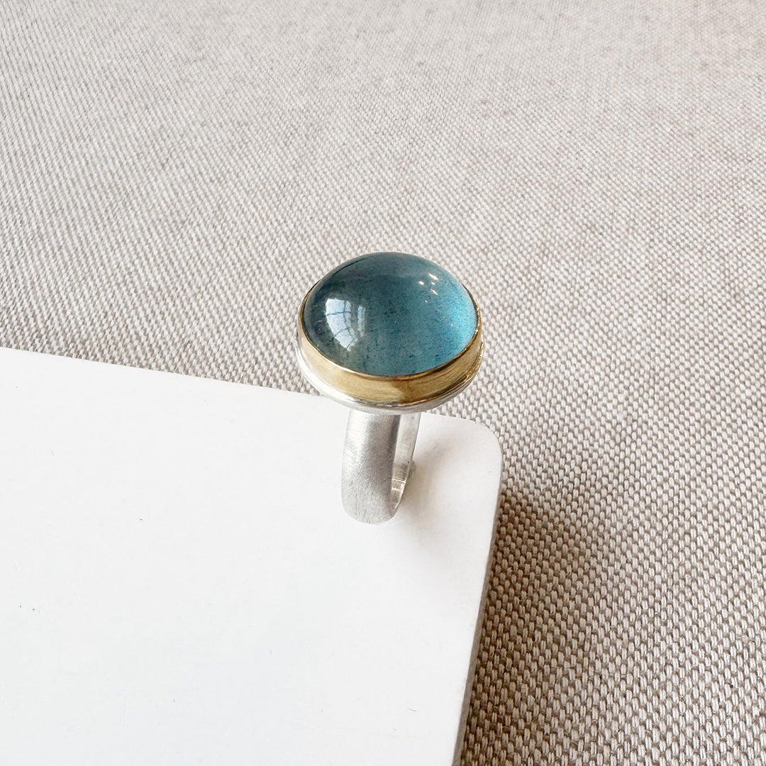 Ring with a blue aquamarine stone on a white surface