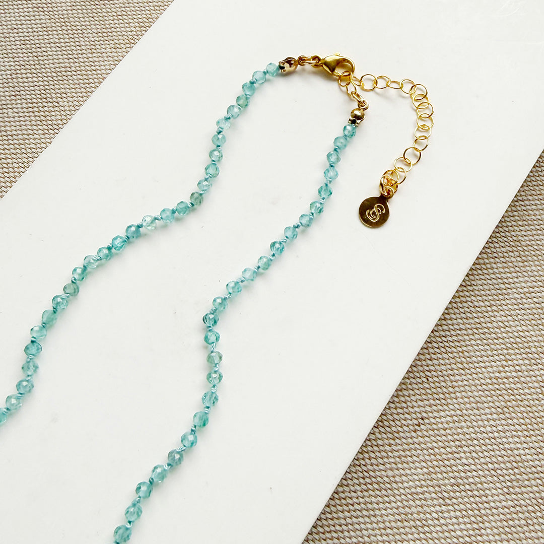 Clasp detail of bright blue apatite gemstone knotted necklace on a white background
