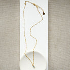 Blue gemstone pendant on a gold chain in a white dish