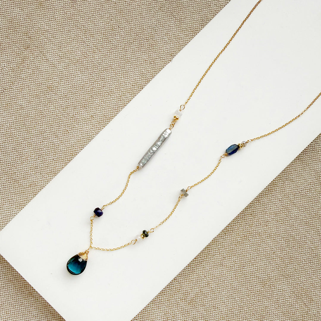 Gold necklace with mixed gems and pearls on a white background