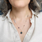Person wearing gold necklace with mixed gems and pearls 