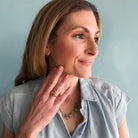 Woman wearing a gold ring and necklace against a light blue background