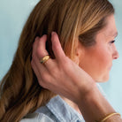 Close up of woman wearing gold dome ring with a light blue background