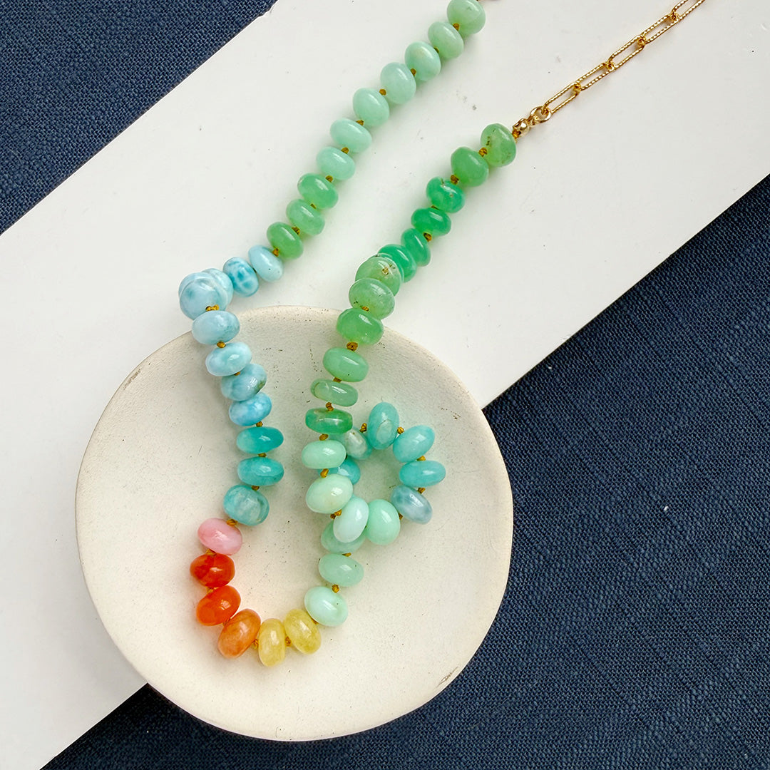 Gemstone beaded necklace on a white dish against a blue background