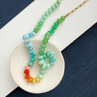 Gemstone beaded necklace on a white dish against a blue background