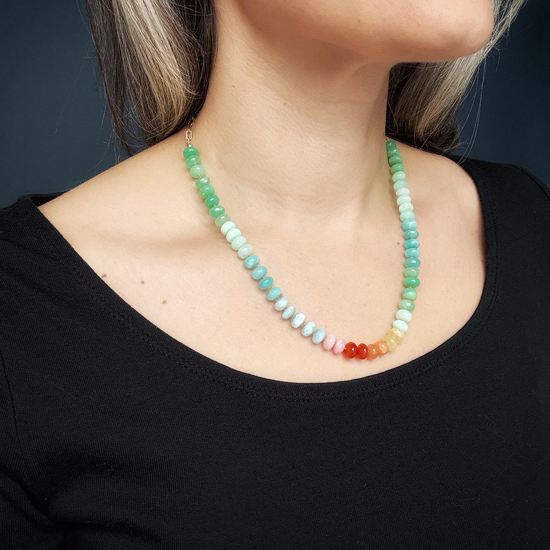 Necklace with multicolored gemstone beads worn by a person against a dark background