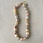 Champagne and rose baroque pearl necklace on a textured beige background