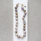 Champagne and rose baroque pearl necklace on a white dish and textured beige background
