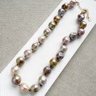 Champagne and rose baroque pearl necklace on a white dish and textured beige background