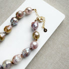 Champagne and rose baroque pearl necklace on a white dish and textured beige background