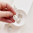 Keshi pearl charm with large gold ring in a white dish.