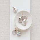 Keshi pearl charm with large gold ring in a white dish.