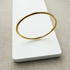 Gold bangle bracelet on a white surface