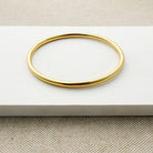 Gold bangle bracelet on a white surface
