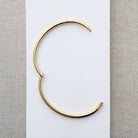 Hinged gold bangle bracelet on a white surface