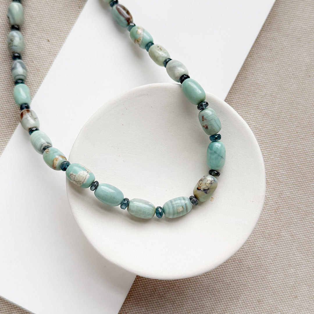 Necklace with teal agate beads on a white dish against a beige background