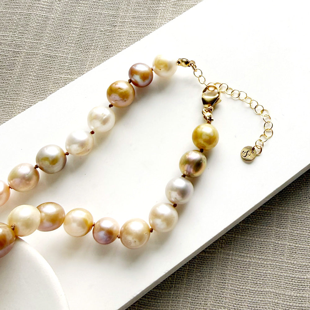 Clasp detail of a champagne pearl knotted necklace in a white dish