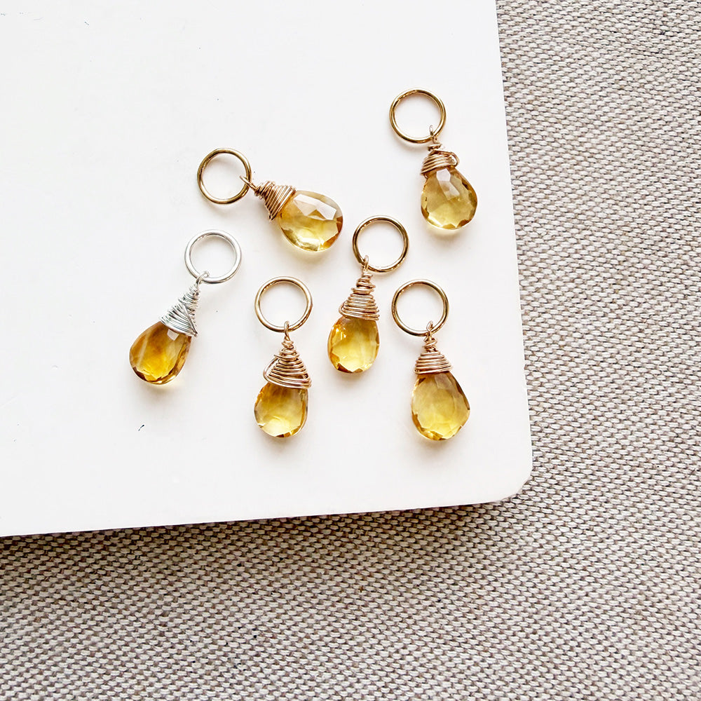 Citrine teardrop shaped charms on a white background