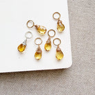 Citrine teardrop shaped charms on a white background