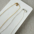 Clasp detail for gold and silver chain necklaces on a white card with a gray background
