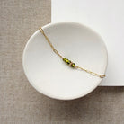 Gold bracelet with green beads on a white dish