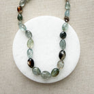 Close up of necklace with copper aquamarine gemstones on a white dish