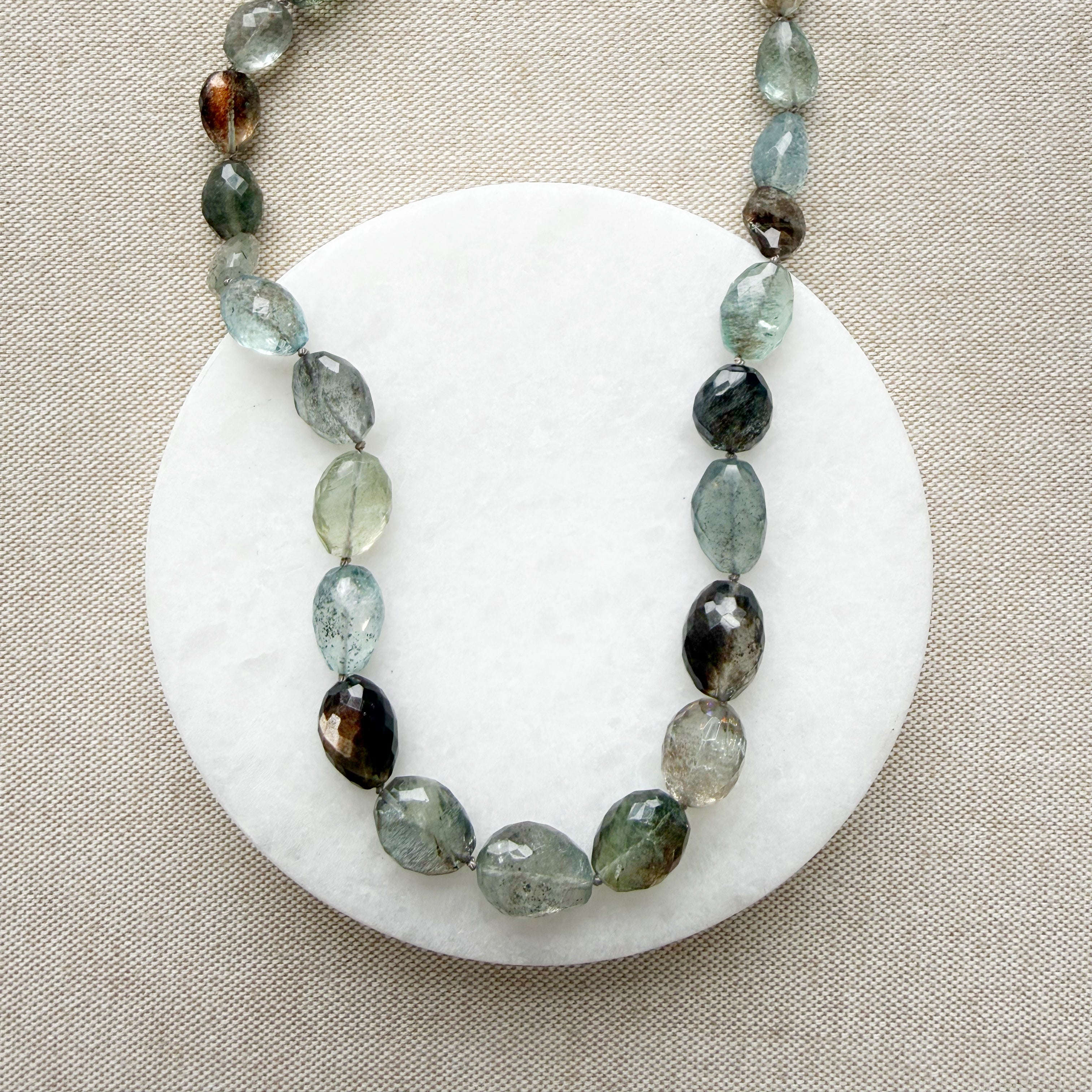 Close up of necklace with copper aquamarine gemstones on a white dish