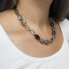 Close up of necklace with faceted copper aquamarine gemstones worn by a person against a dark background