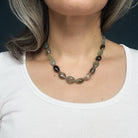 Necklace with copper aquamarine gemstones worn by a person against a dark background
