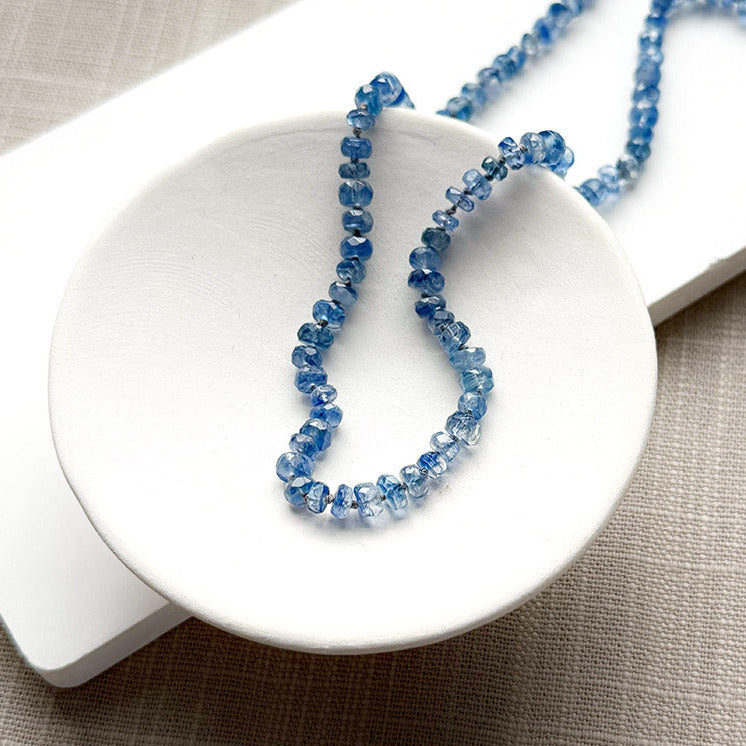 Blue kyanite knotted gem necklace in a white dish
