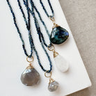 Three necklaces with stone pendants on a beige surface