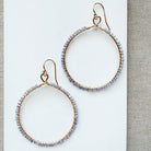 Large hoop earring hand wire wrapped in small tanzanite stones on a white background