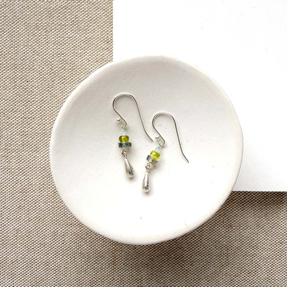 gemstone earrings with silver teardrop accent in a white dish