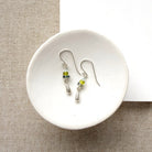 gemstone earrings with silver teardrop accent in a white dish