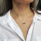 Necklace with a labradorite gemstone worn by a person in a white shirt