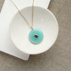 Round chalcedony pendant on a gold chain in a white dish