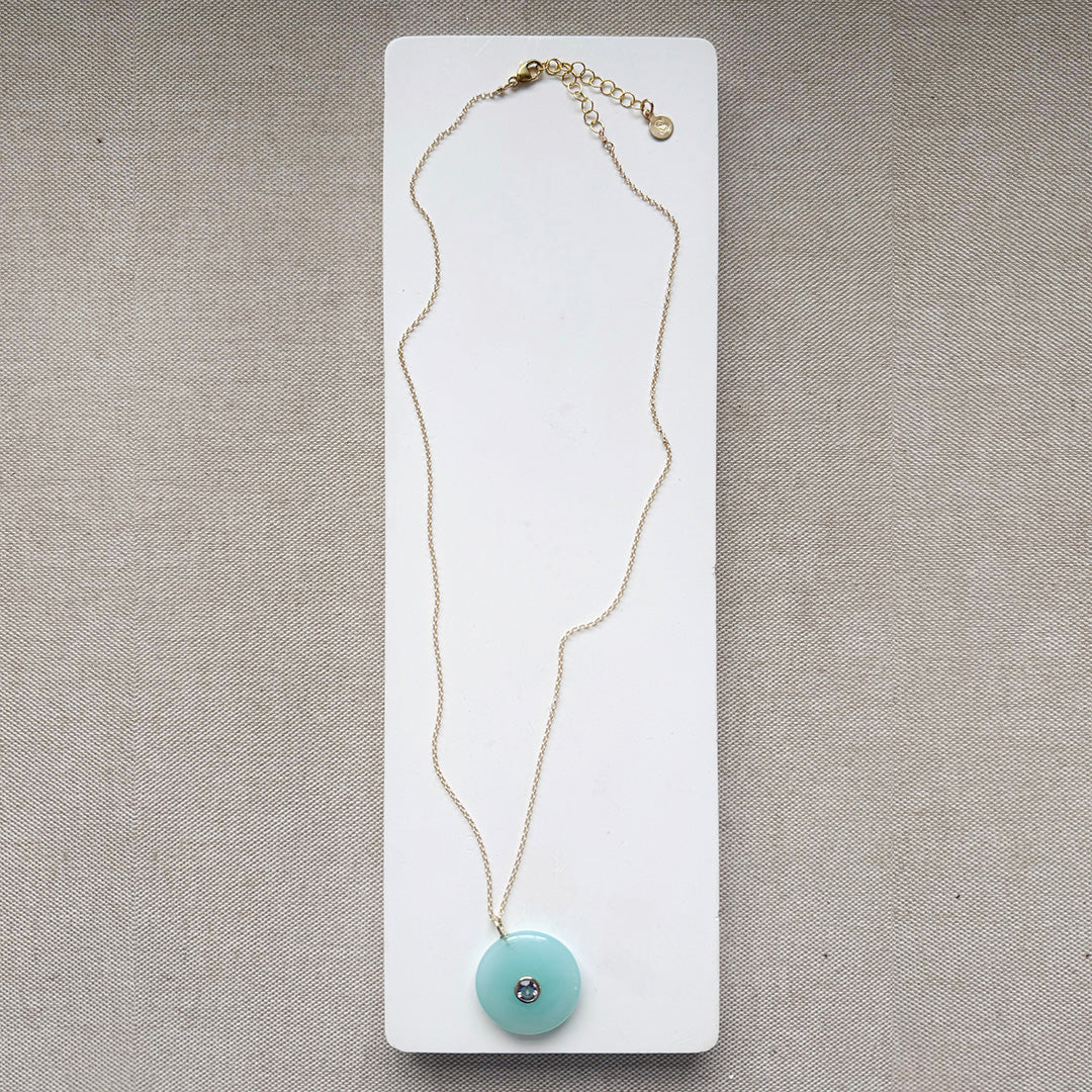 Round chalcedony pendant on a gold chain on a white card