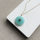 Round chalcedony pendant on a gold chain on a white card