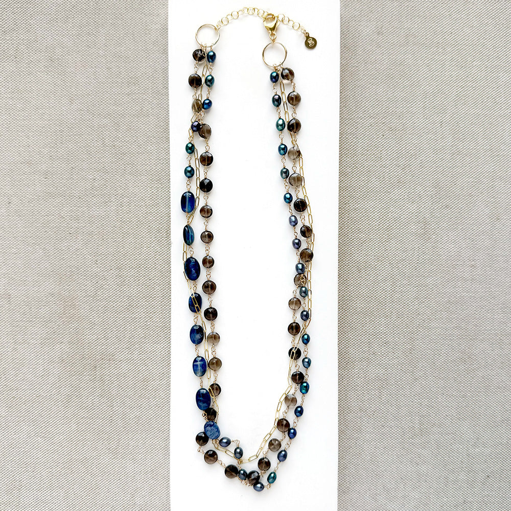 Multi strand necklace with kyanite and smokey quartz on a white plate