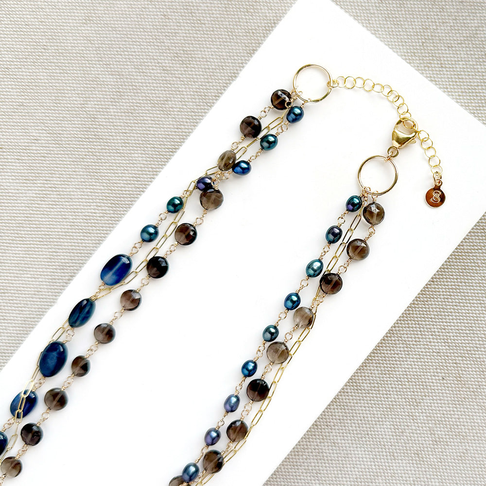 Multi strand necklace with kyanite and smokey quartz on a white plate