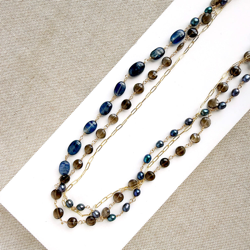 Multi strand necklace with kyanite and smokey quartz on a white plate