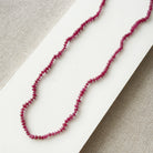 Small ruby gems knotted necklace on a light gray background