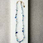 Gemstone necklaces in shades of blue on a white surface