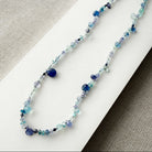 Gemstone necklaces in shades of blue on a white surface